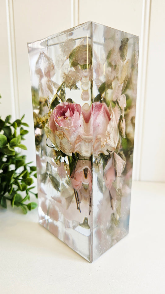 Clear resin block with preserved flowers on a white surface