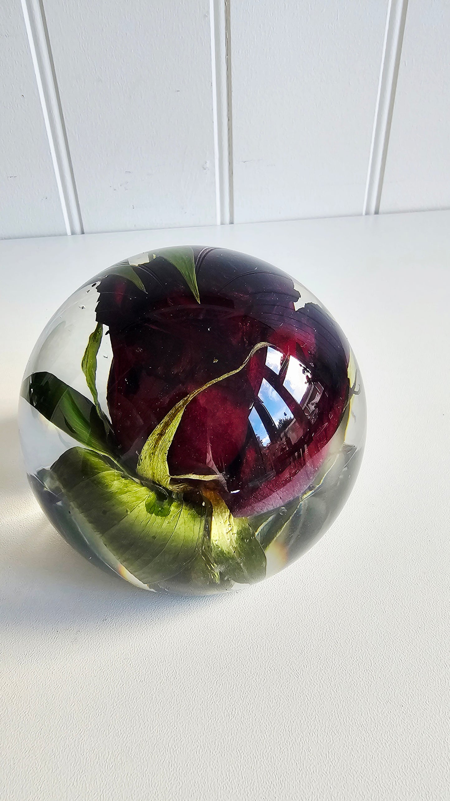 resin paperweight with a red wedding rose encapsulated on a white surface top view