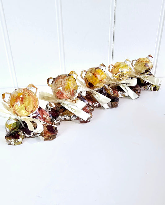 Decorative resin bears full of red adn orange funeral flowers preserved on a white background