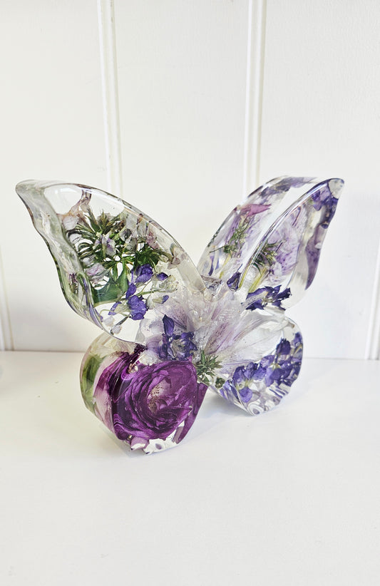 clear resin butterfly figurine with preserved wedding flowers on a white background side view