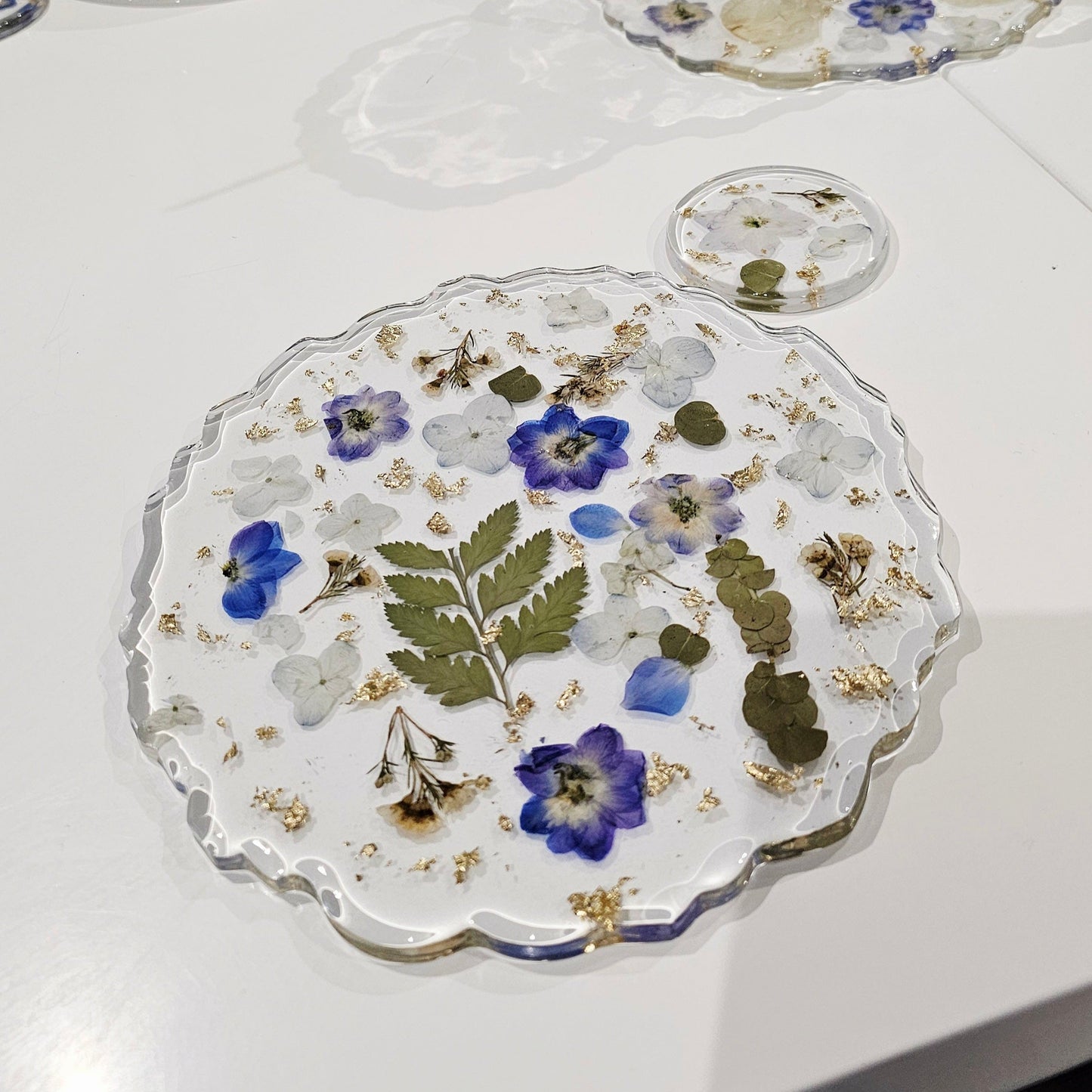 Decorative resin placemats with floral designs on a white table.