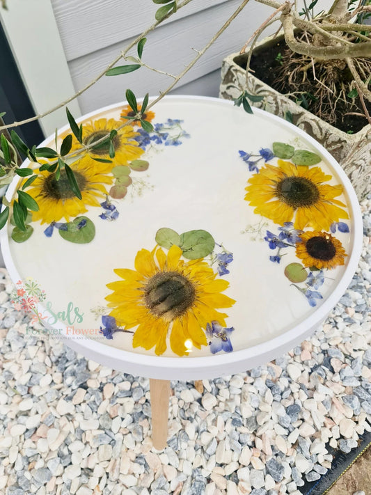 Decorative resin table with sunflowers and greenery on a pebbled surface