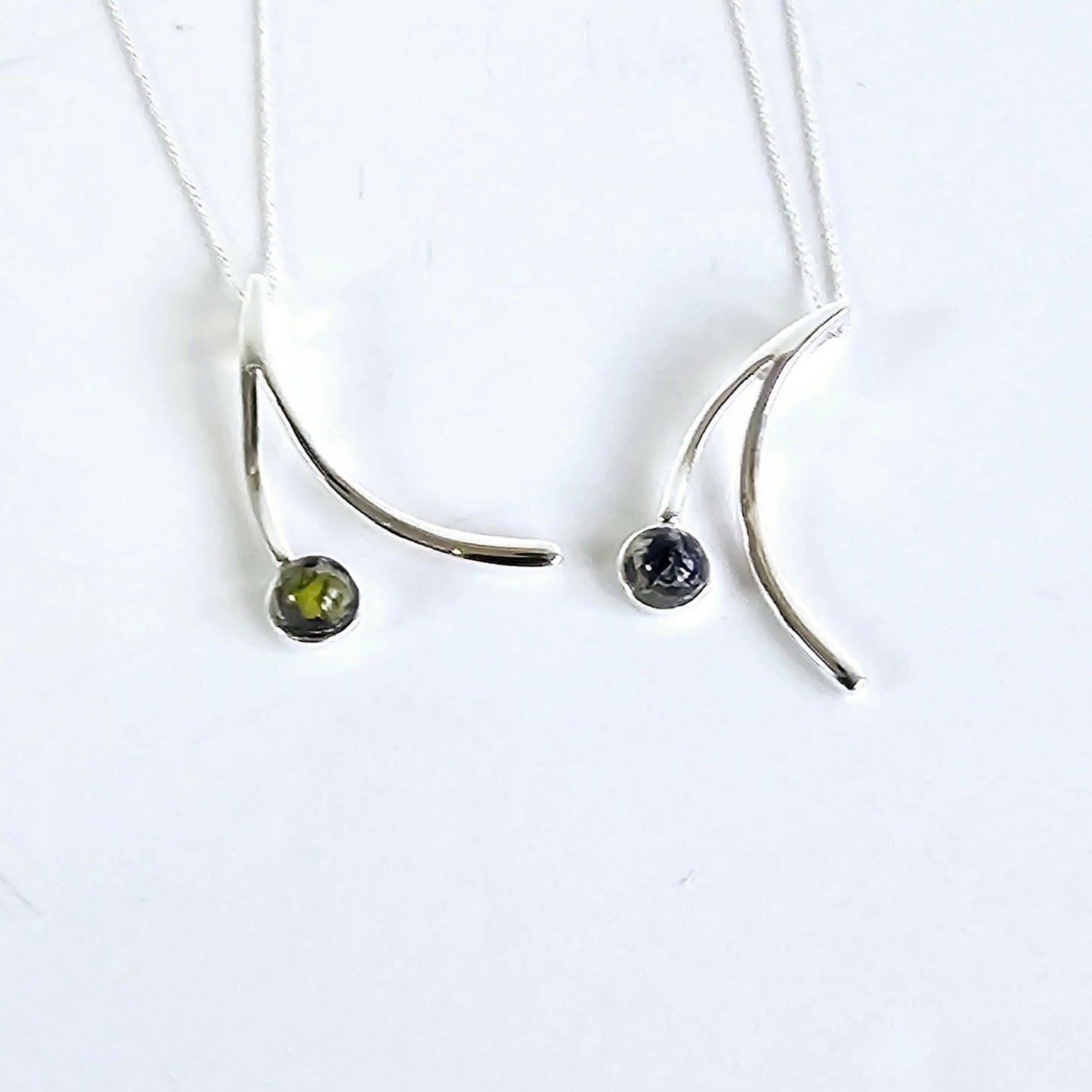 2 sterling silver drop necklaces with flower preserved in resin on one side on a white background