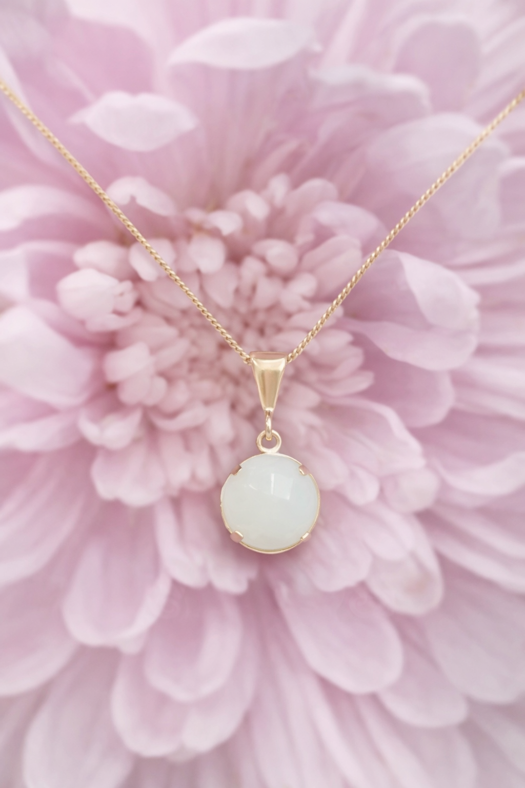 Gold necklace with a breastmilk.preservation pendant on a pink flower background