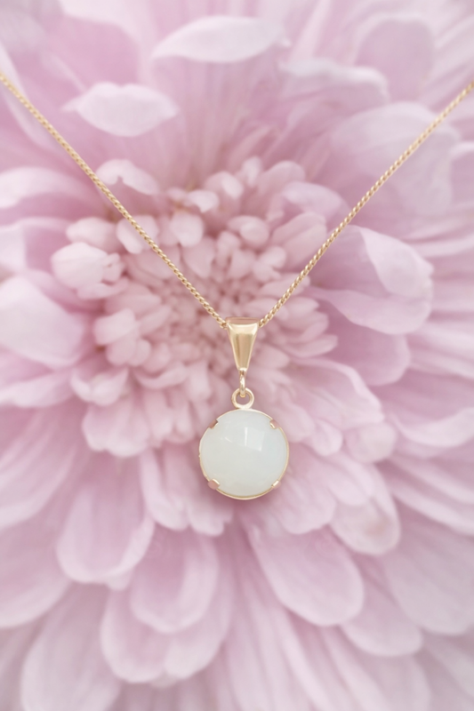 Gold necklace with a breastmilk.preservation pendant on a pink flower background