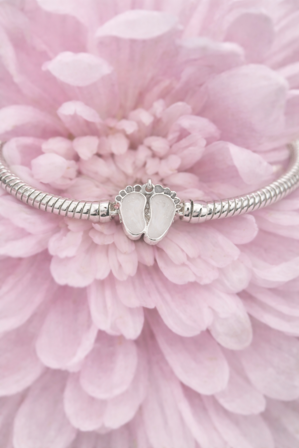 Silver charm with baby feet with preserved breastmilk on a pink flower