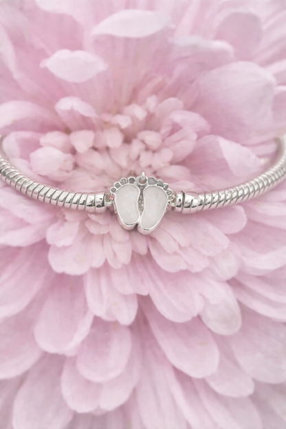 Silver charm with baby feet with preserved breastmilk on a pink flower