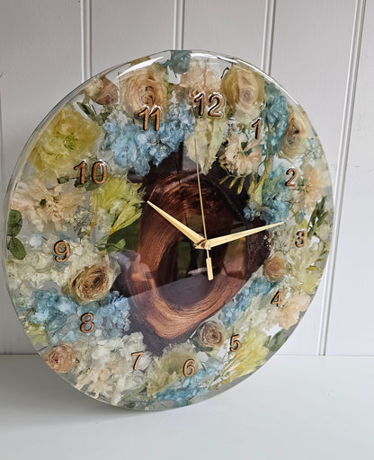 Decorative resin wall clock with a wedding bouquet preserved within jt displayed on a white wall