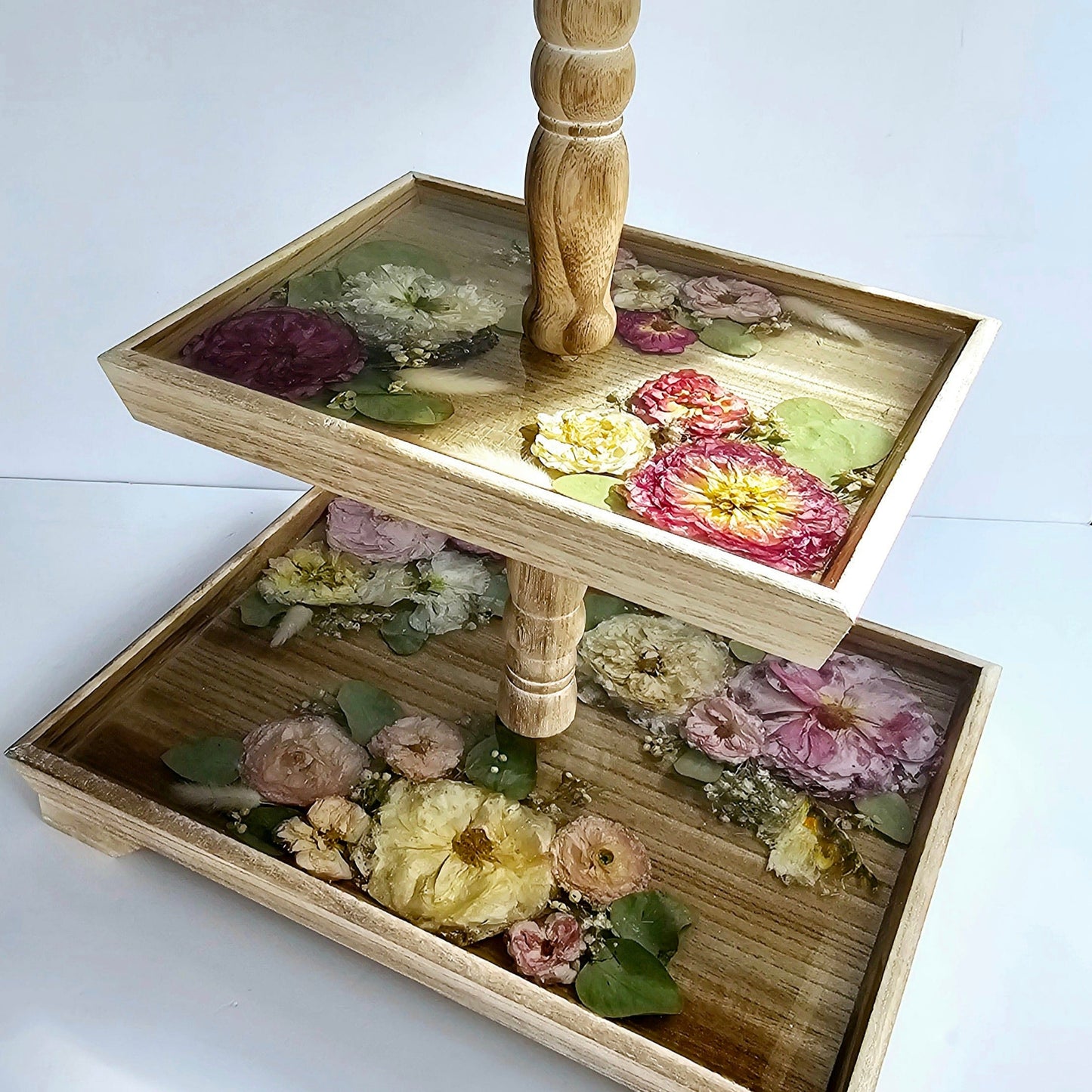 Two-tier wooden tray with floral decorations on a white background