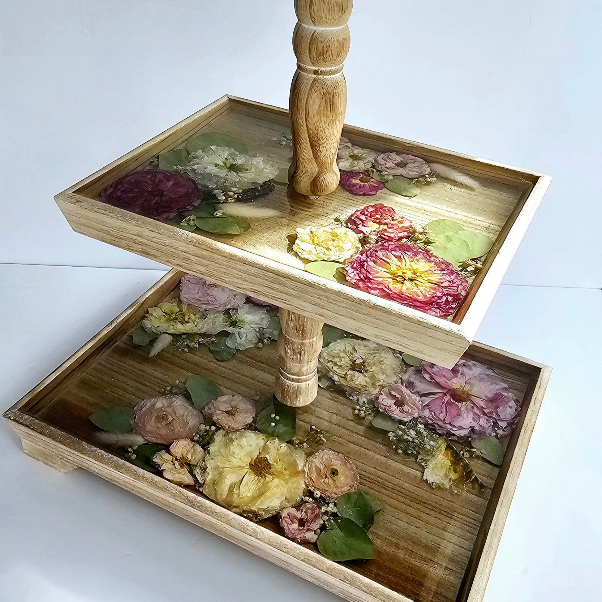 Two-tier wooden tray with floral decorations on a white background