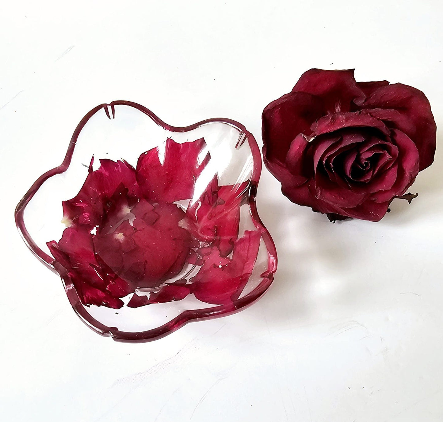 flower shaped resin bowl with red flowers and a single red rose on a white background
