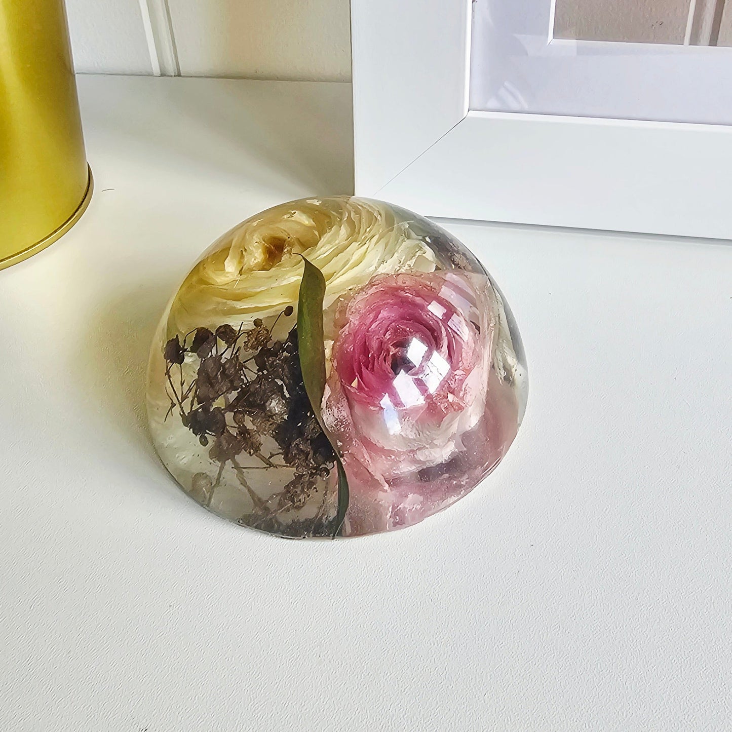 Decorative resin paperweight with floral design on a white surface.