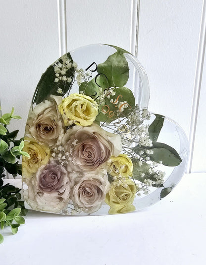 Clear resin heart with preserved flowers including roses and greenery on a white background