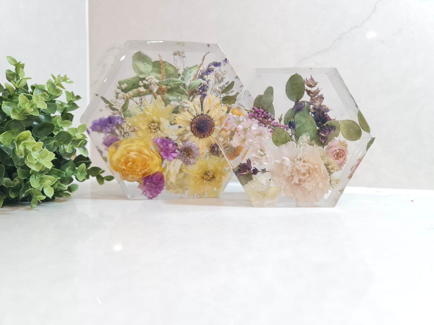 Hexagonal resin decorative items with pressed flowers on a white background