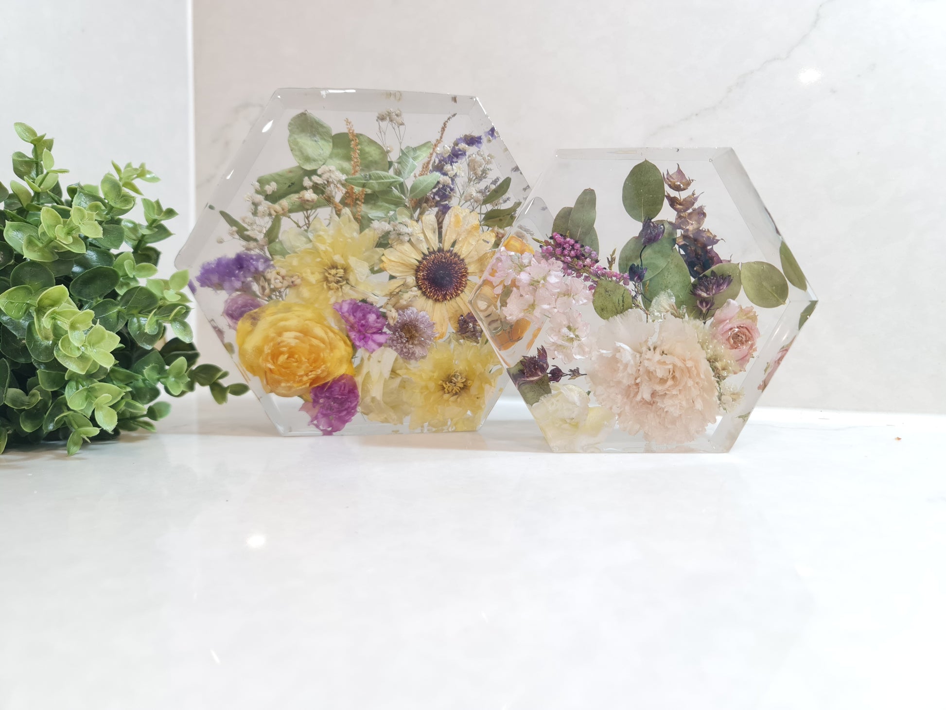 Hexagonal resin decorative items with pressed flowers on a white background