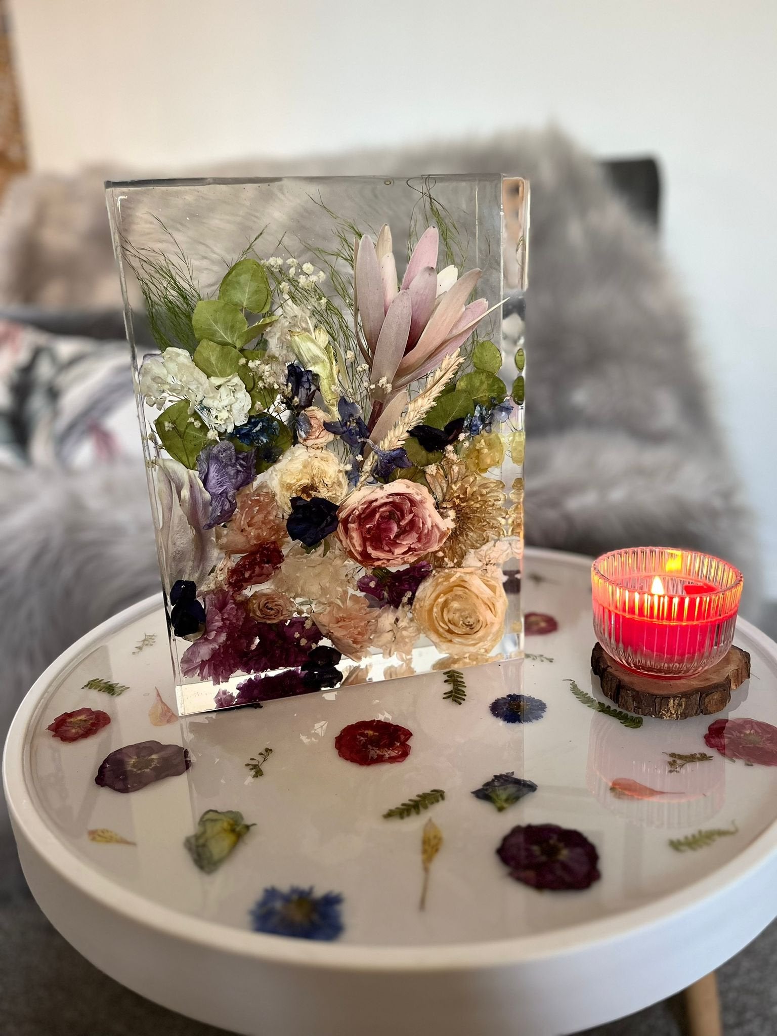 resin block with pressed flowers on a floral table with a lit candle