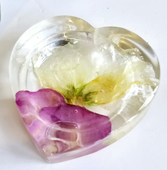 Heart-shaped clear resin mold with a purple flower and yellow center on a white background