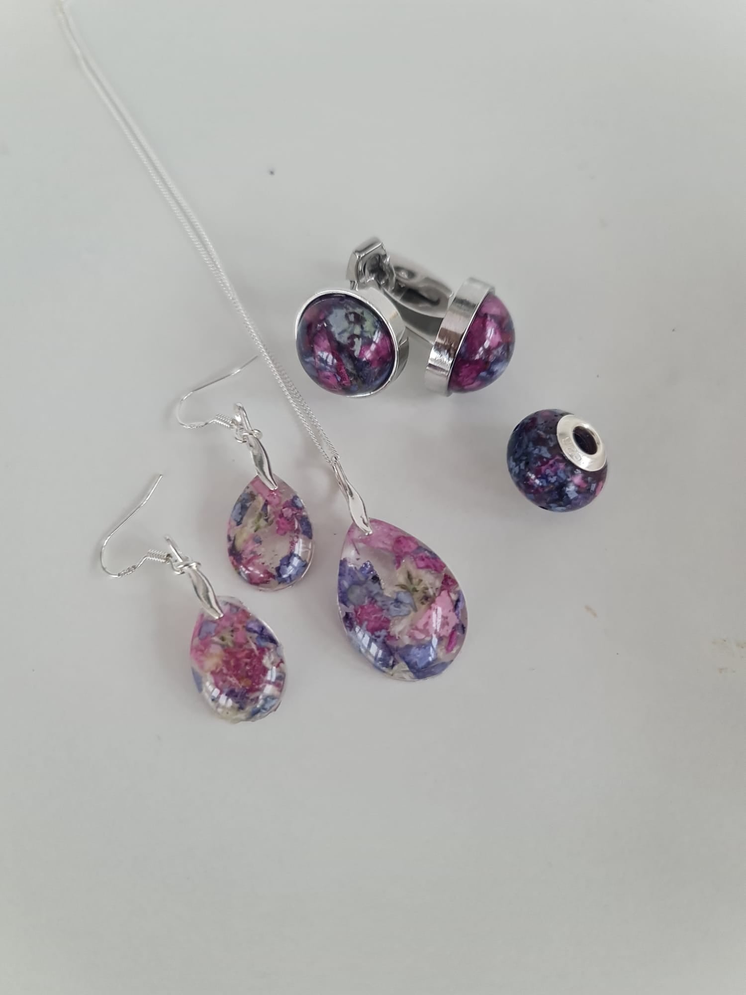 Jewellery set with floral earrings and a matching pendant on a light gray background