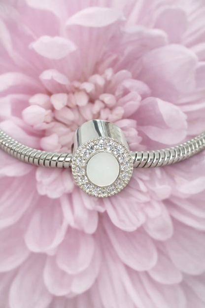 Silver breatmilk breservation bracelet charm on a pink floral background