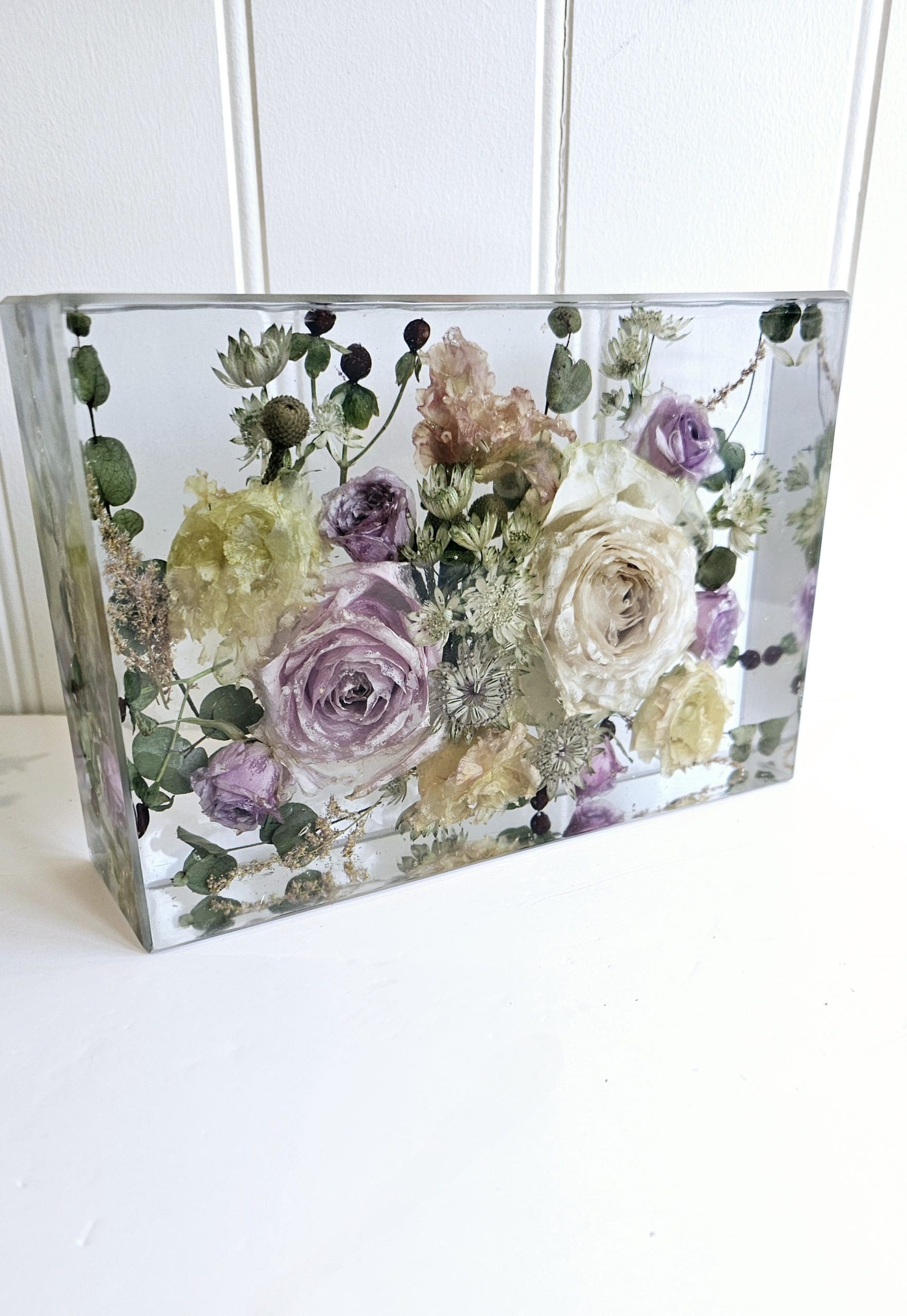 Clear resin block with pressed flowers on a white background