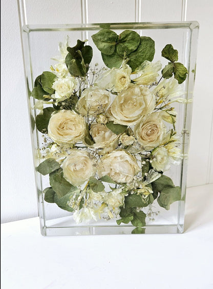 Clear resin block with white roses and greenery against a white background