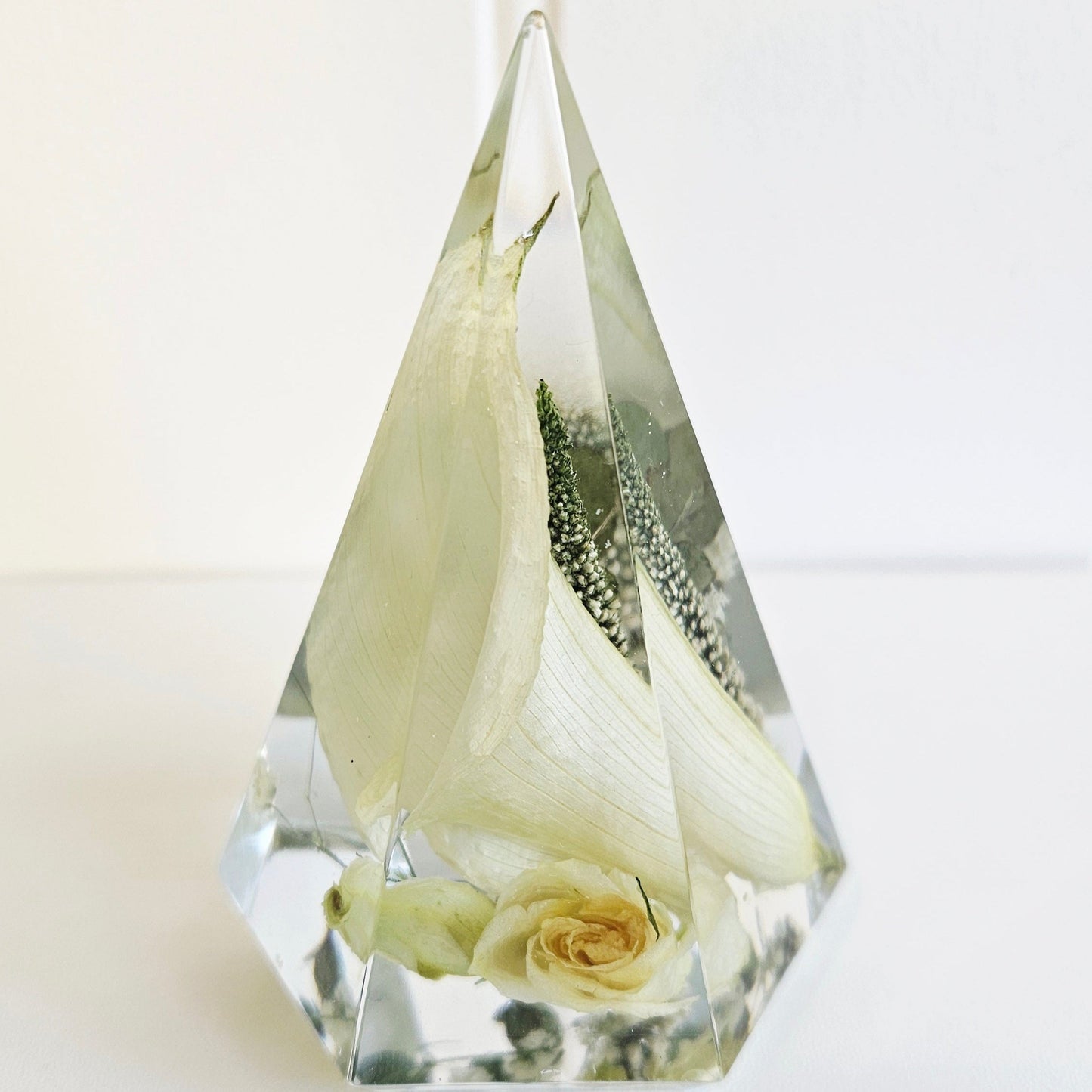 Clear resin pyramid ring holder with preserved white rose and baby’s breath wedding flowers inside.