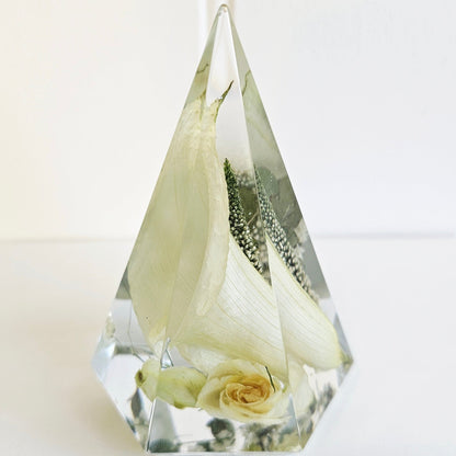 Clear resin pyramid ring holder with preserved white rose and baby’s breath wedding flowers inside.