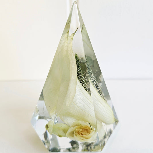 Clear resin pyramid ring holder with preserved white rose and baby’s breath wedding flowers inside.