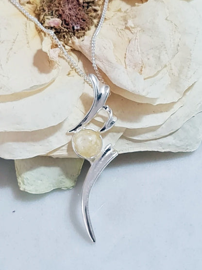 Silver pendant with a white rose preserved within it on a marble background 