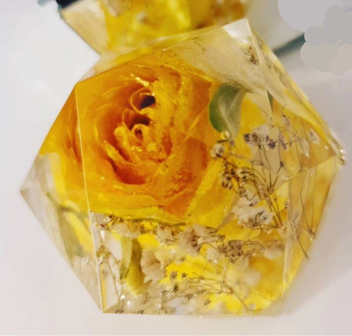 Hexagonal resin ornament with a yellow rose and dried flowers inside on a white background