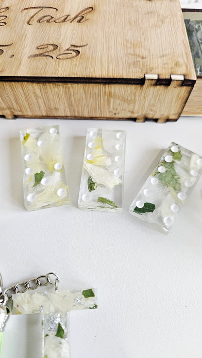Set of clear resin jewelry with floral designs on a white surface, next to a wooden box.
