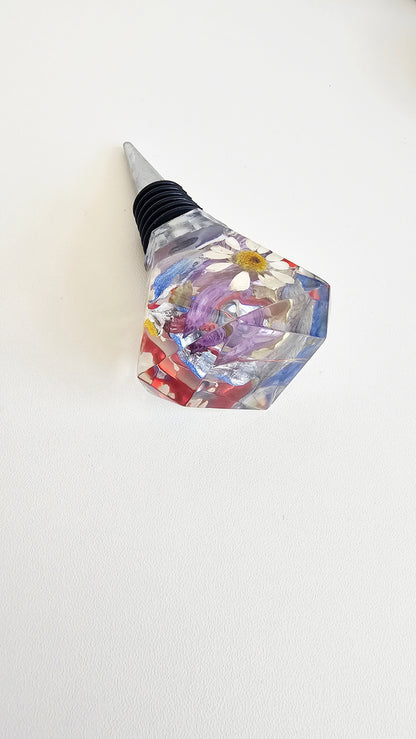 Decorative resin wine bottle stopper with colourful geometric design on a white background