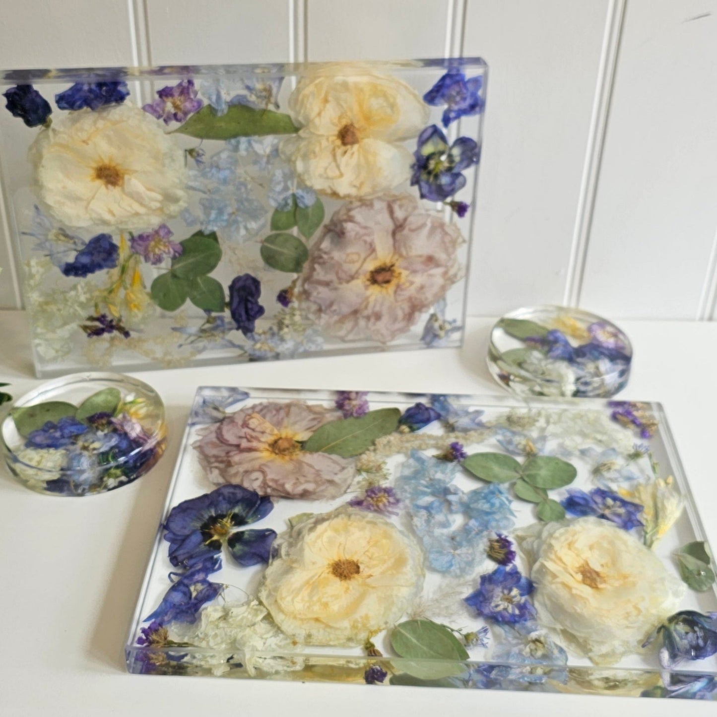 2 placemats and 2 matching coasters made from clear epoxy resin with flowers encapsulated within them
