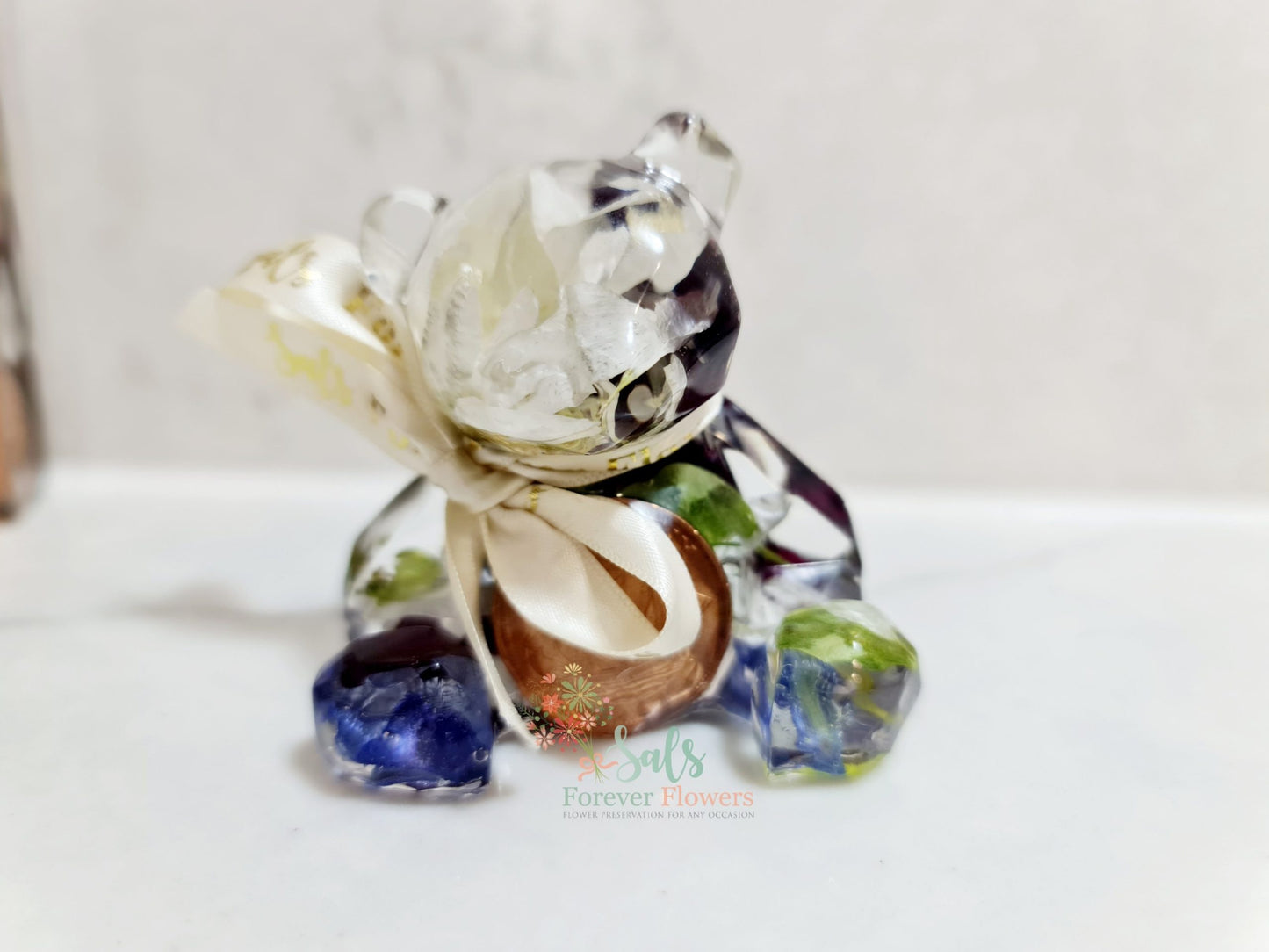 Decorative resin figurine of a bear with coloured flowers on a white background