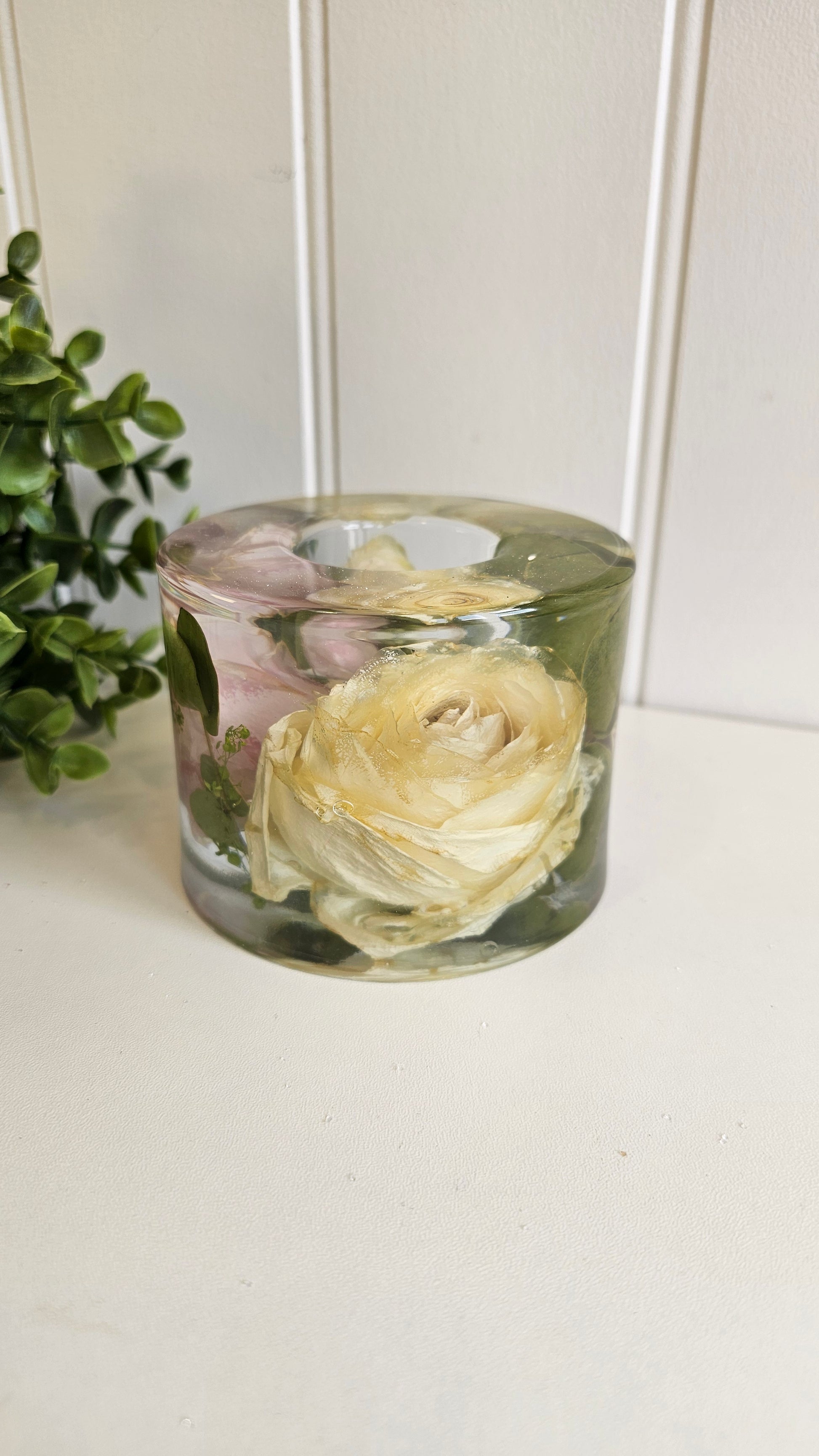 Clear cylindrical vase with preserved flowers against a white background