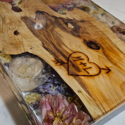 Wooden block with embedded flowers and a heart-shaped engraving on a white surface