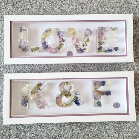 Two framed decorative letters spelling 'LOVE' and 'K8' on a textured surface.