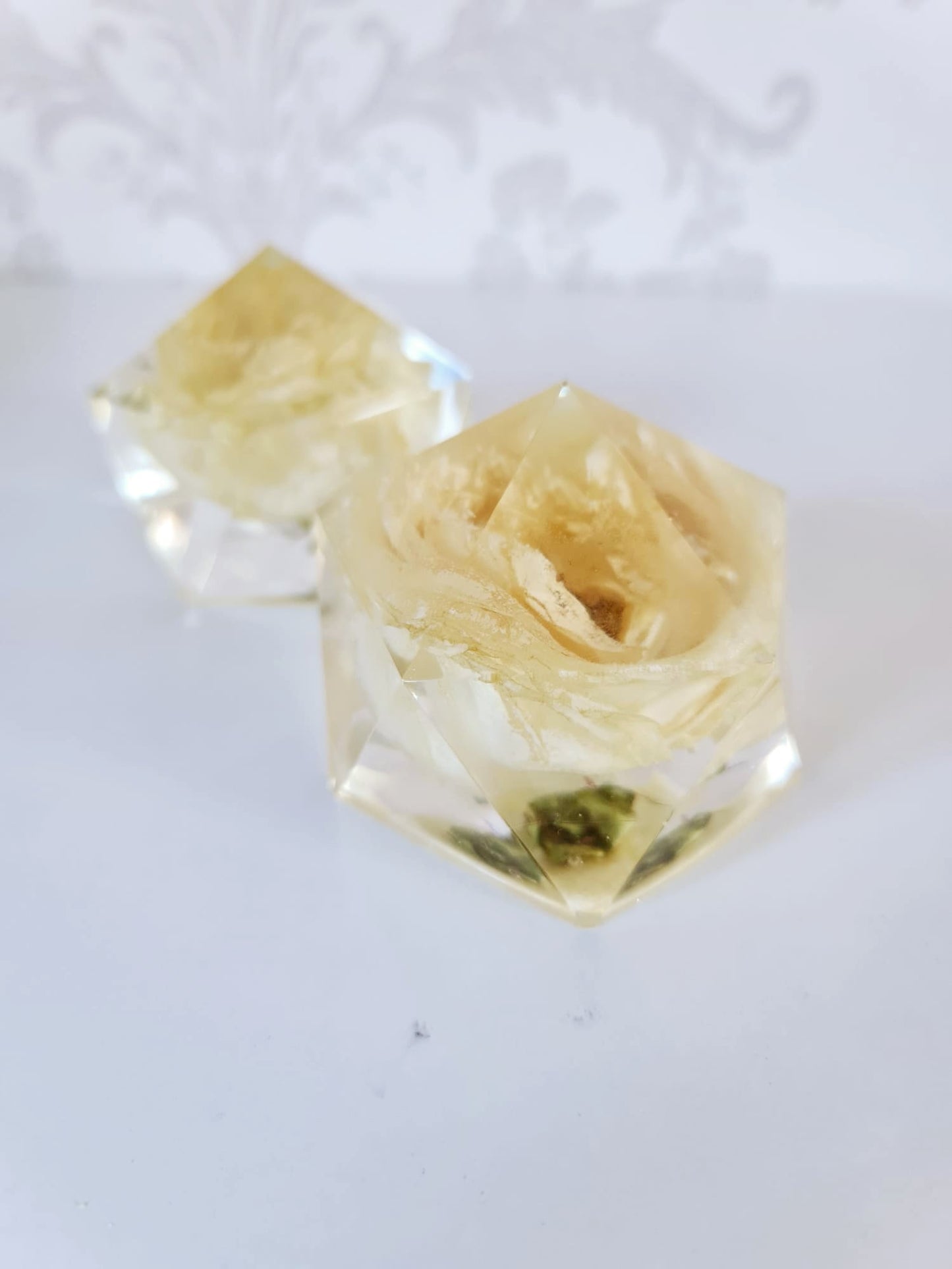 Clear resin paperweight with a white funeral rose preserved within it on a white background