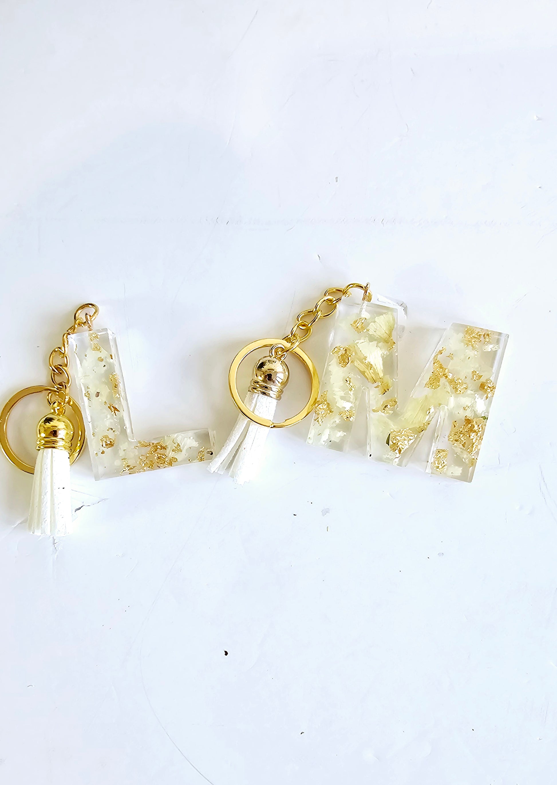 2 resin initial keyrings L and M full of white flowers on a white background