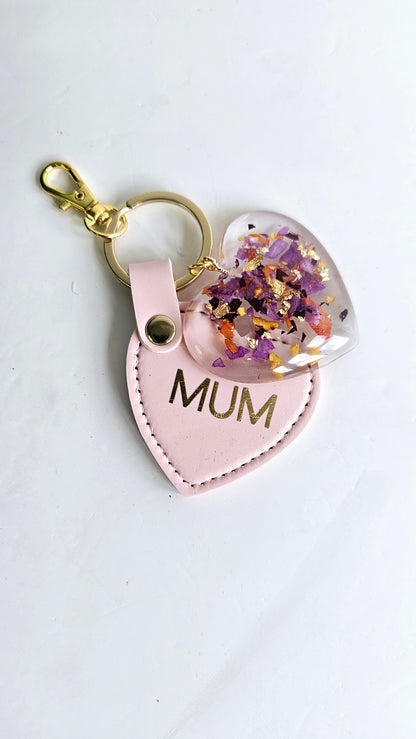 Heart-shaped keychain with 'MUM' and floral design on a white background