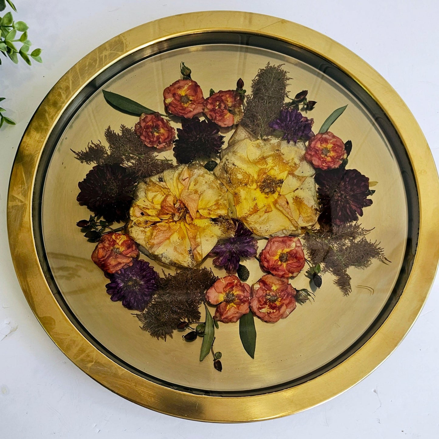 Round decorative tray with floral design and gold rim on a white surface