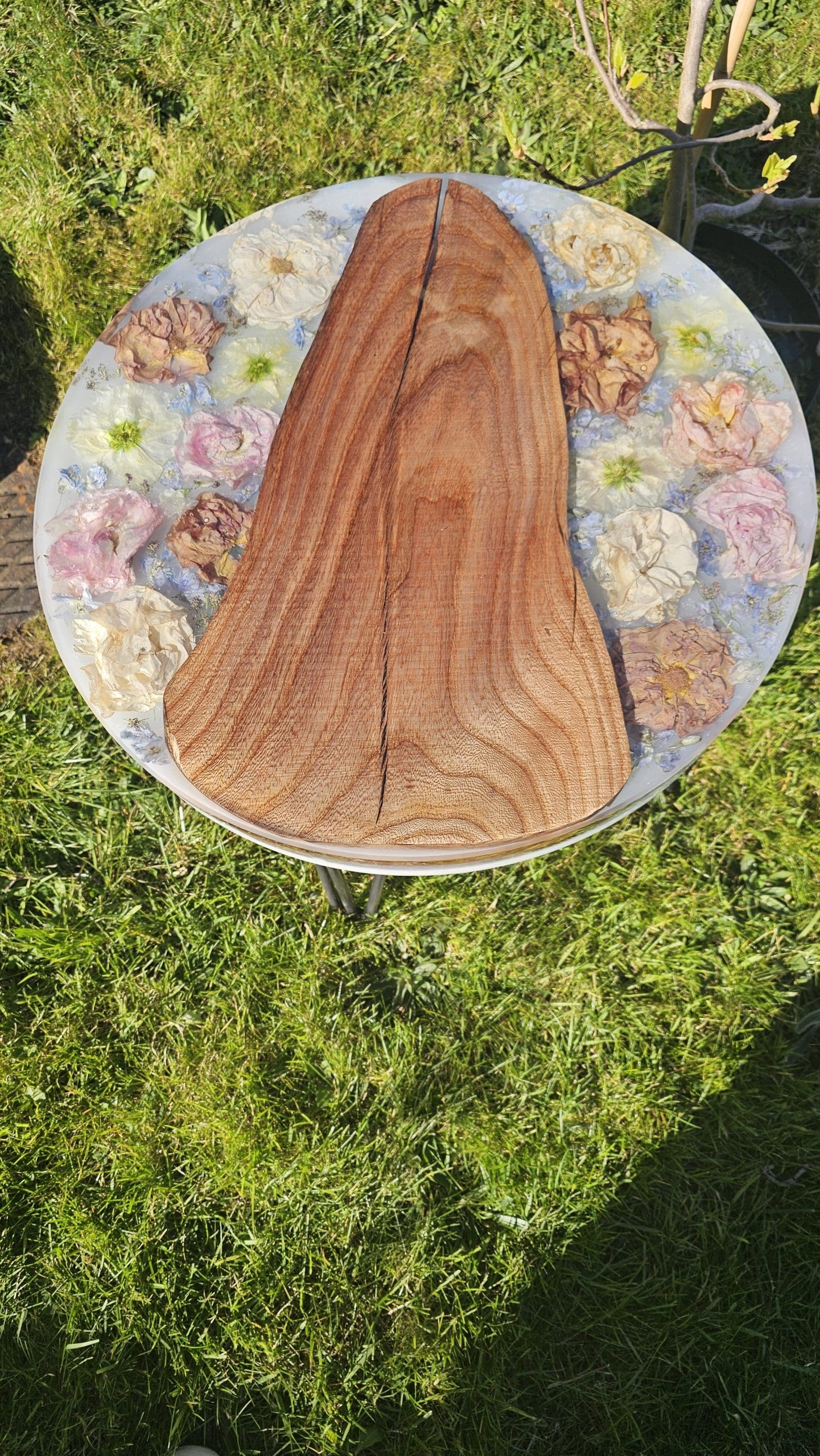 Wooden surface with floral arrangement on a grassy background