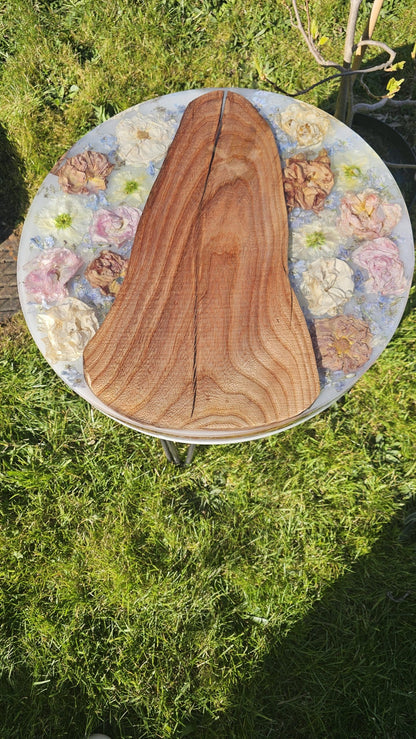 Wooden surface with floral arrangement on a grassy background
