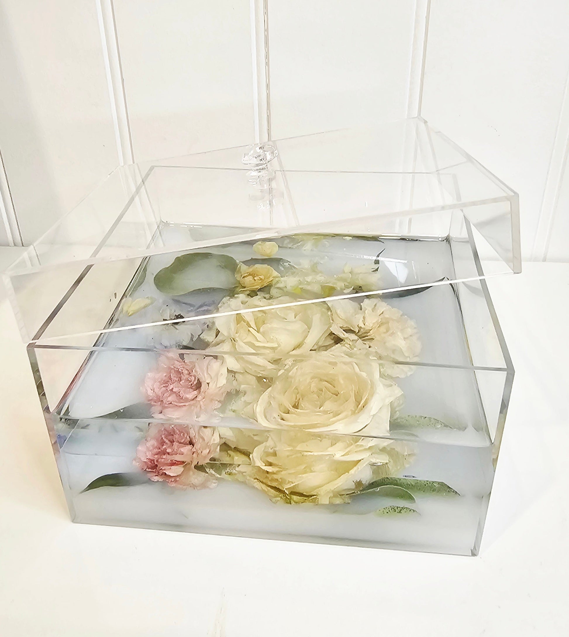 Transparent box with preserved flowers on a white background