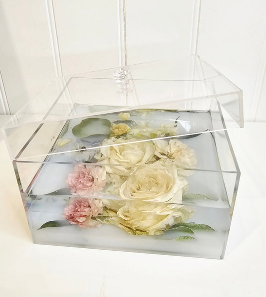 Transparent box with preserved flowers on a white background
