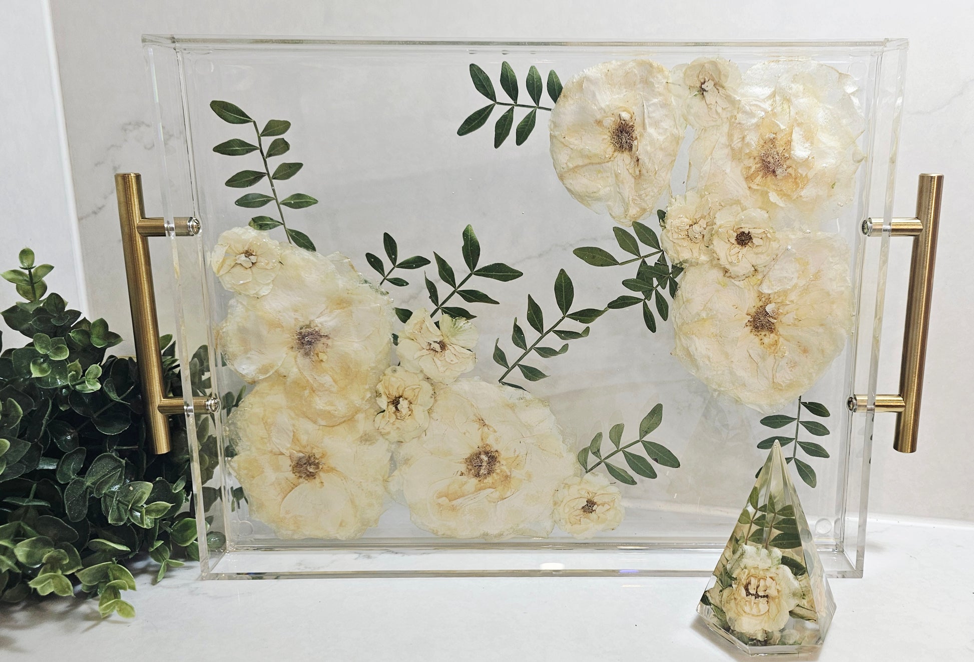 Decorative tray with floral design and gold handles on a white surface.