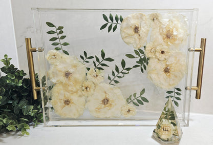 Decorative tray with floral design and gold handles on a white surface.