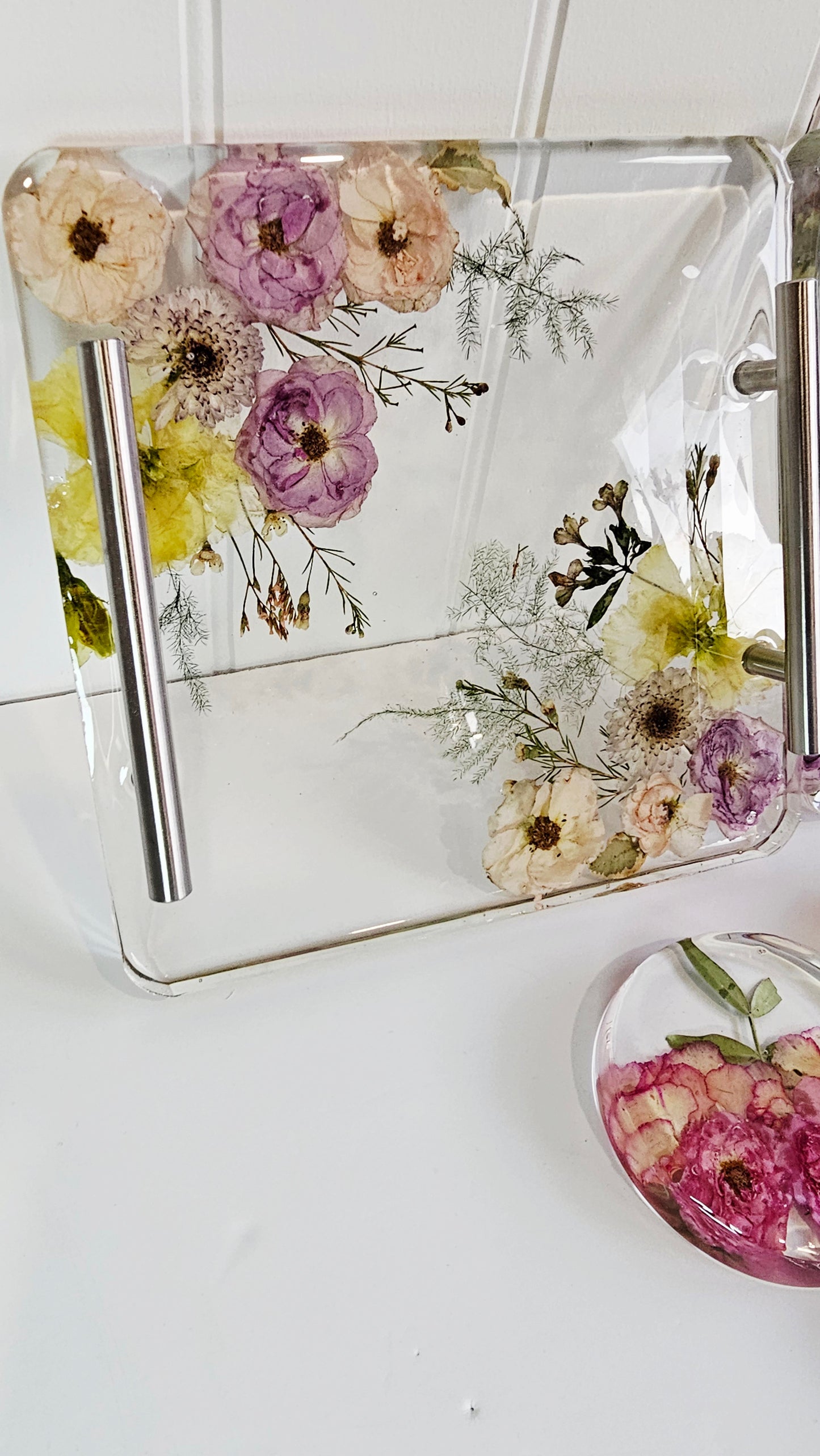 Clear resin tray with pressed flowers on a white surface
