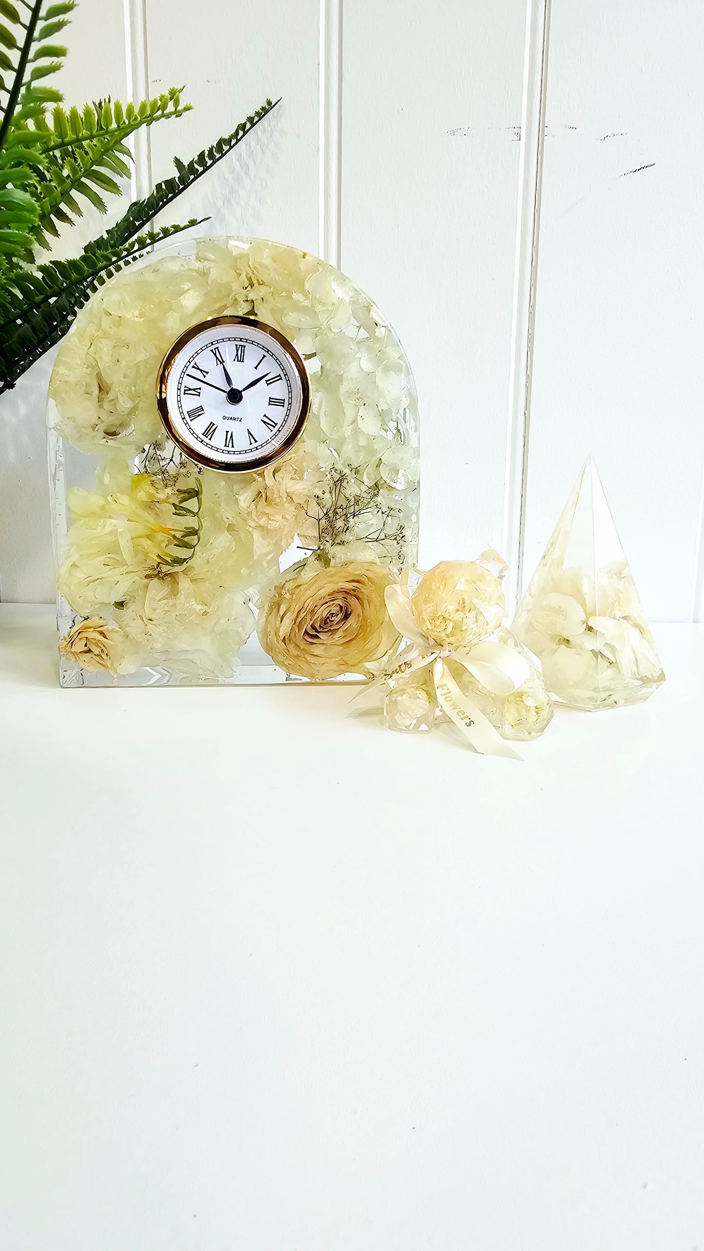 Decorative clock with flowers in a clear vase on a white background