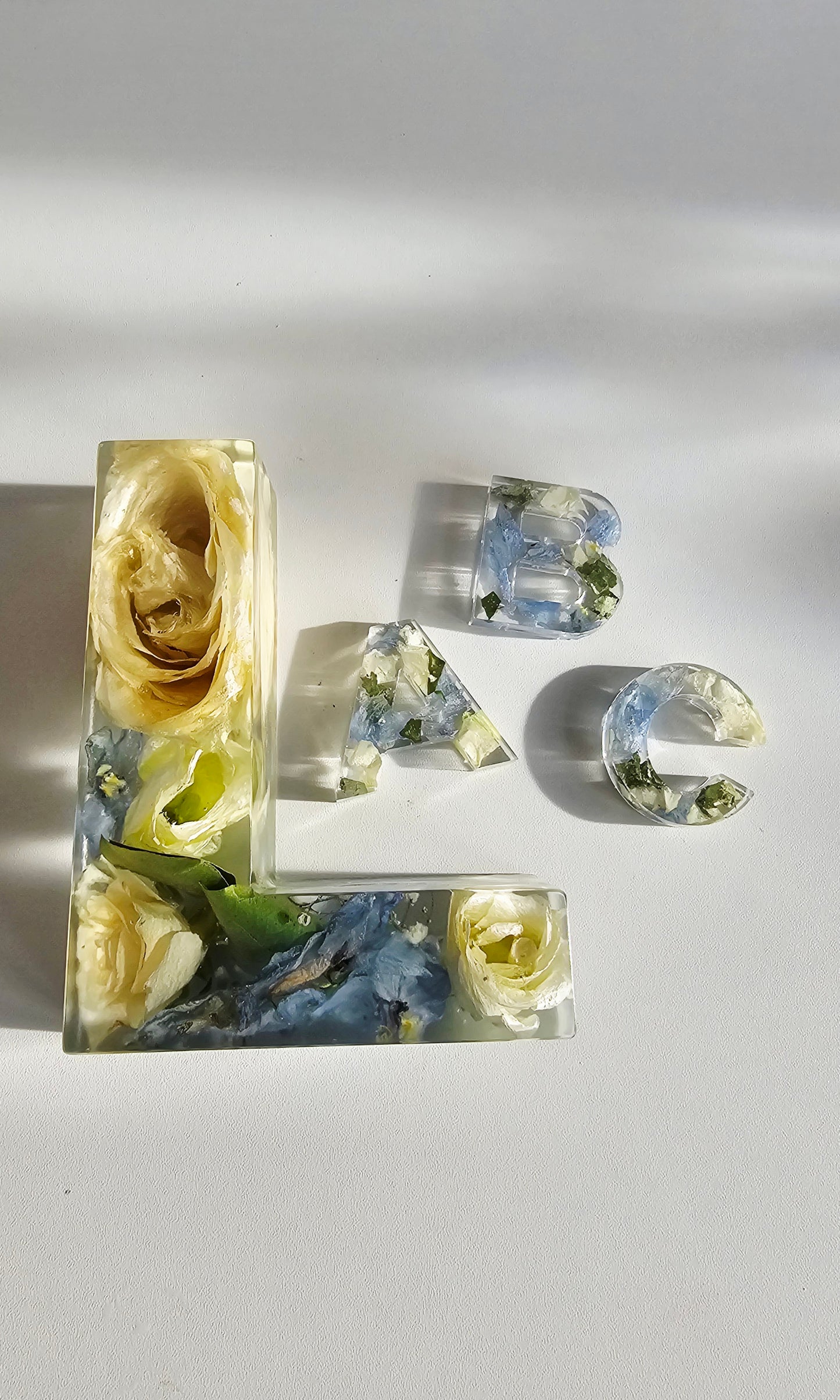 Decorative letters 'L', 'A', and 'C' made of pressed flowers on a light background